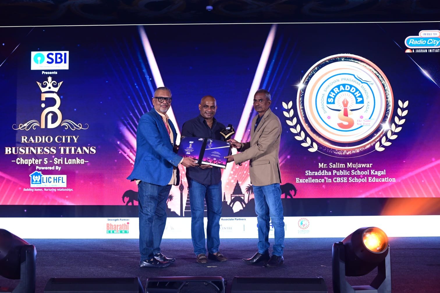 Mr. Salim Mujawar receiving an award from former cricketer Sanath Jayasuriya on a stage in Colombo, Sri Lanka